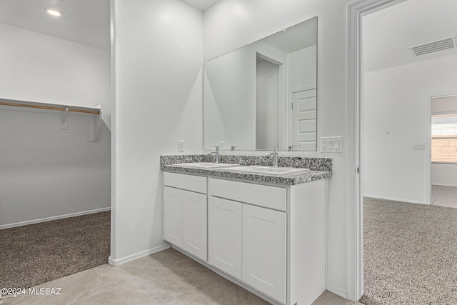 bathroom with double vanity, visible vents, a spacious closet, and a sink