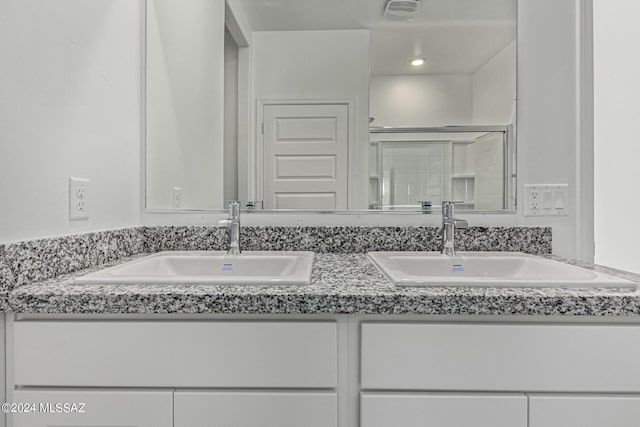 full bath featuring double vanity, a sink, a shower stall, and visible vents