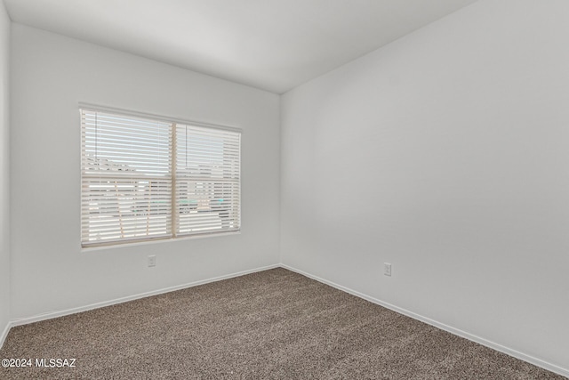carpeted empty room featuring baseboards