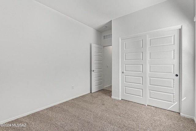 unfurnished bedroom with a closet, visible vents, light colored carpet, and baseboards