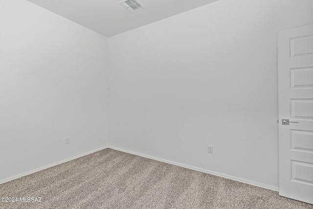 empty room featuring visible vents, light colored carpet, and baseboards