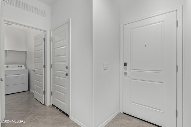 hall with light tile patterned floors, visible vents, and washer / clothes dryer