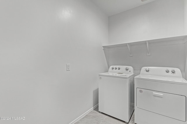 laundry area featuring baseboards, light tile patterned floors, washing machine and clothes dryer, and laundry area