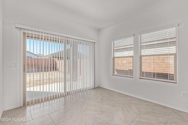 spare room featuring light tile patterned flooring and baseboards