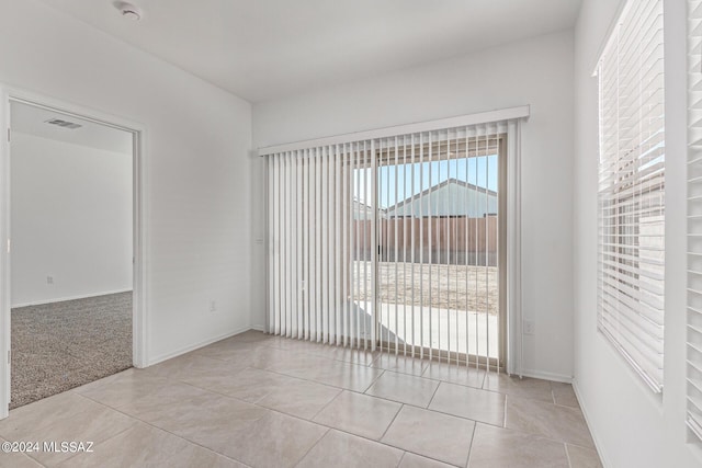 unfurnished room with light tile patterned floors, visible vents, and baseboards