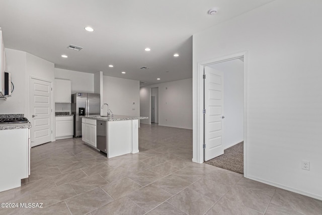 kitchen featuring white cabinets, appliances with stainless steel finishes, visible vents, recessed lighting, and a center island with sink