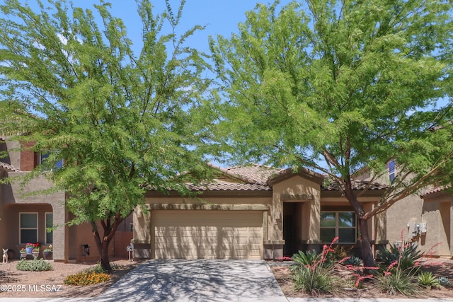 mediterranean / spanish home featuring stucco siding, concrete driveway, a tile roof, and a garage