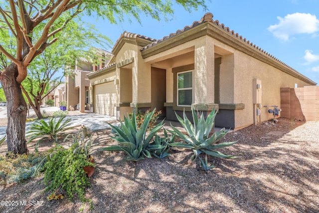 view of front of home with a garage, stucco siding, driveway, and a tiled roof