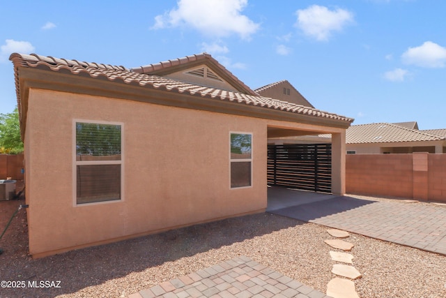 view of side of home with fence, a patio, and stucco siding