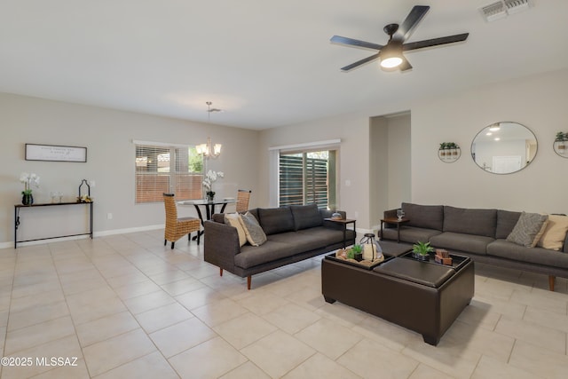 living room with light tile patterned floors, visible vents, baseboards, and ceiling fan with notable chandelier