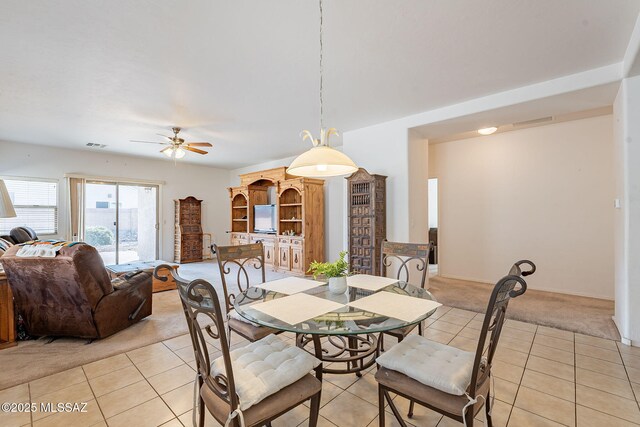 dining room featuring visible vents, light tile patterned floors, a ceiling fan, and light carpet