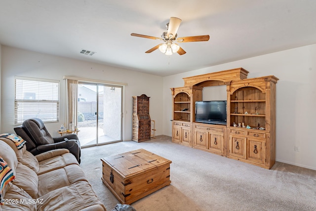 living area featuring visible vents, a ceiling fan, and light carpet