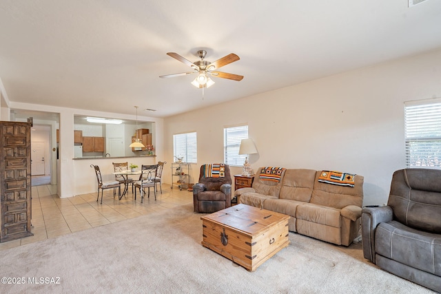 living area with a healthy amount of sunlight, light tile patterned floors, a ceiling fan, and light colored carpet