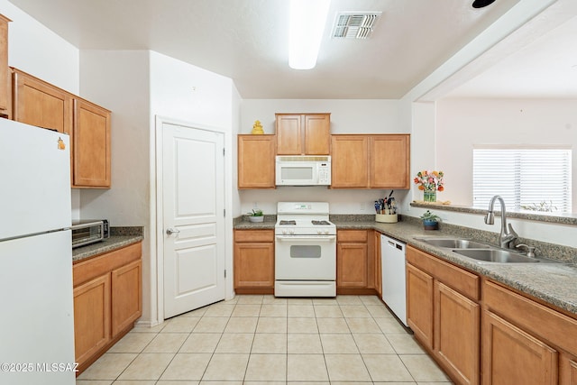 kitchen featuring white appliances, brown cabinets, a sink, visible vents, and light tile patterned flooring