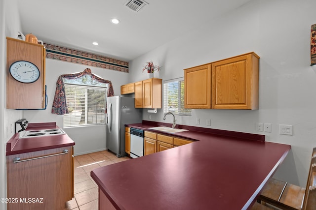 kitchen with a sink, dark countertops, stainless steel refrigerator with ice dispenser, visible vents, and dishwasher