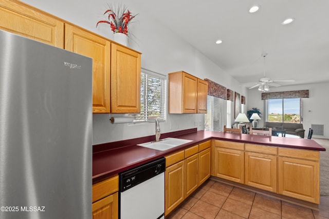 kitchen featuring freestanding refrigerator, a ceiling fan, dishwasher, a sink, and a peninsula