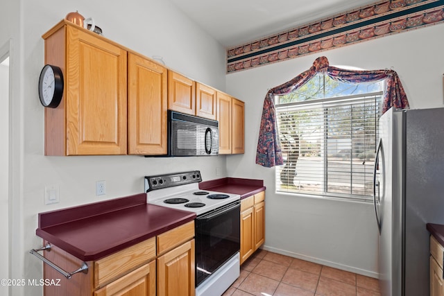 kitchen with freestanding refrigerator, dark countertops, plenty of natural light, electric stove, and black microwave