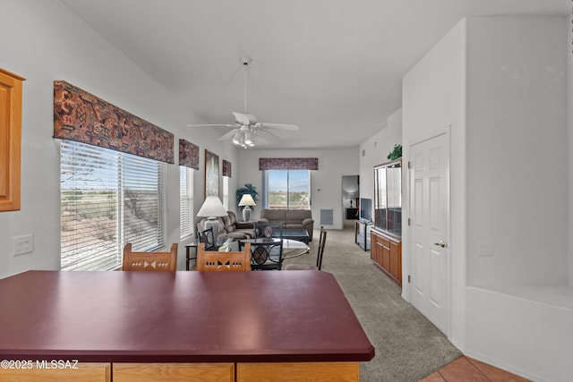 kitchen featuring a ceiling fan, light tile patterned flooring, open floor plan, a peninsula, and light colored carpet