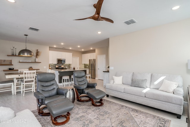 living room with a ceiling fan, recessed lighting, and visible vents