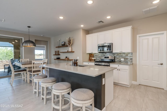 kitchen with a sink, white cabinets, stainless steel appliances, and visible vents