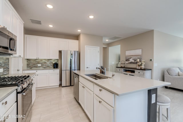kitchen with visible vents, tasteful backsplash, a sink, stainless steel appliances, and white cabinetry