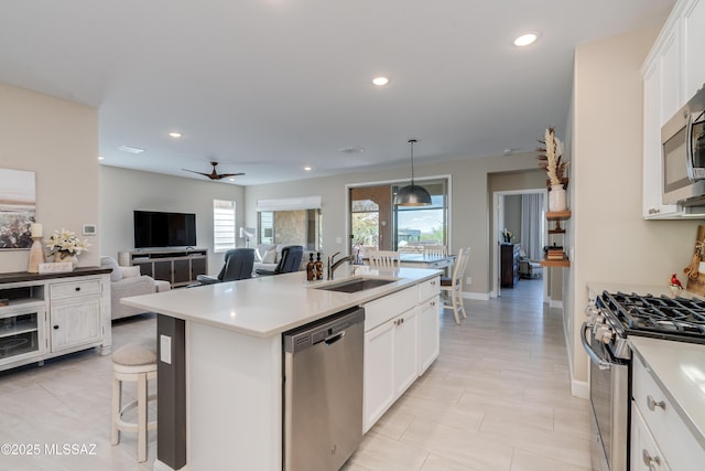kitchen with a sink, light countertops, white cabinets, a ceiling fan, and appliances with stainless steel finishes