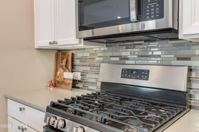 kitchen with backsplash, stainless steel appliances, and white cabinetry