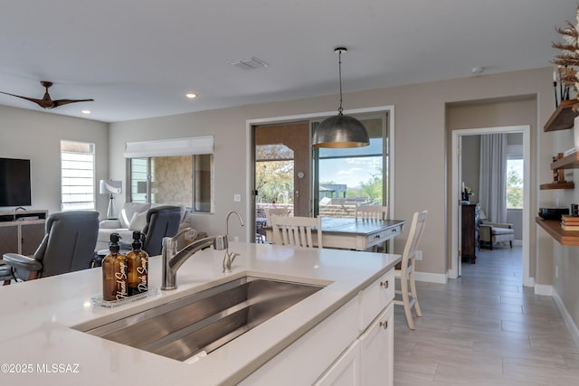 kitchen featuring recessed lighting, light countertops, white cabinets, a sink, and decorative light fixtures