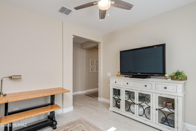living room with baseboards, ceiling fan, and visible vents