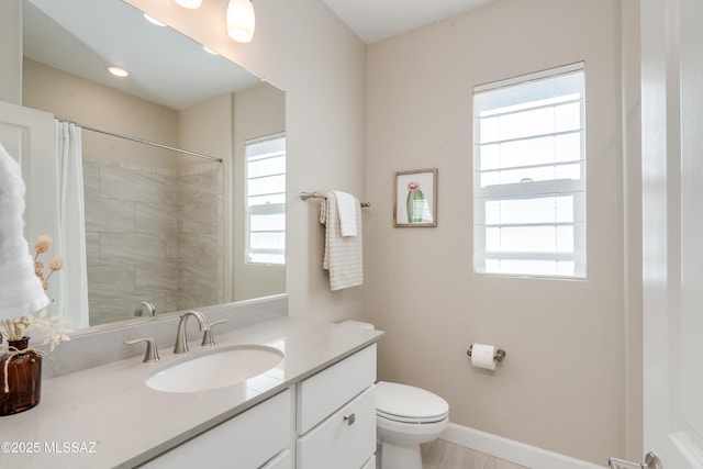bathroom featuring toilet, plenty of natural light, a shower with shower curtain, and vanity