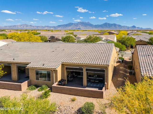 back of property with stucco siding, a mountain view, a patio area, central air condition unit, and a tiled roof
