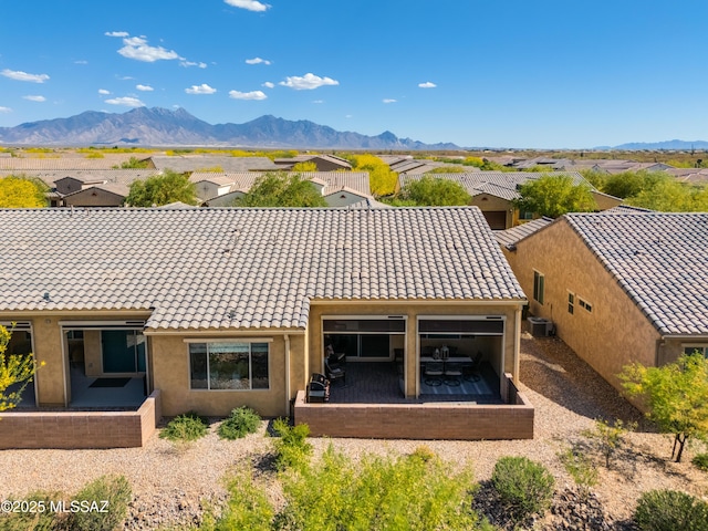 rear view of property with a residential view, a mountain view, a tiled roof, and stucco siding