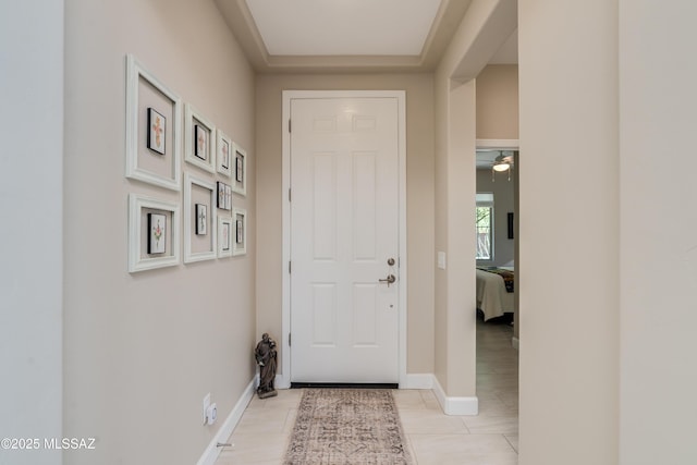 doorway to outside featuring baseboards, ceiling fan, and light tile patterned floors