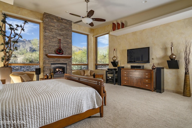 carpeted bedroom featuring a fireplace, a ceiling fan, and a mountain view