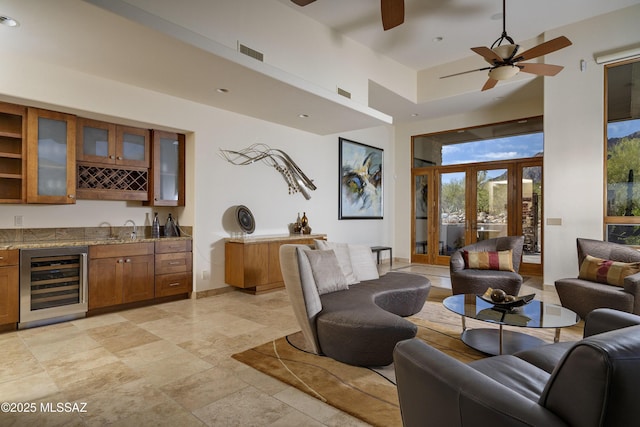 living area with a ceiling fan, wet bar, wine cooler, and a towering ceiling