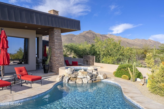 view of pool with an outdoor stone fireplace, a patio, a fenced in pool, and a mountain view
