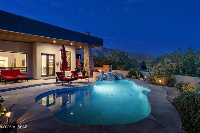 pool at twilight with a fenced in pool, a fenced backyard, a mountain view, french doors, and a patio