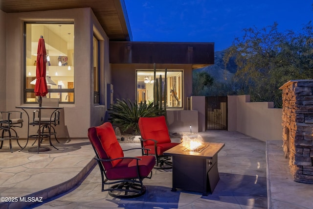 patio at twilight featuring a gate and an outdoor fire pit