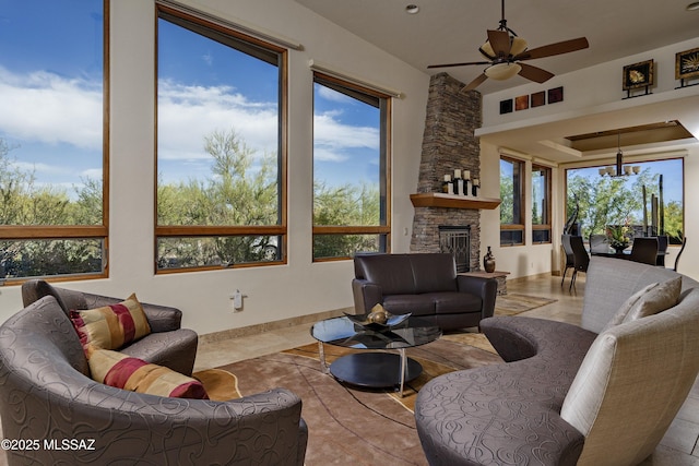 living area featuring ceiling fan with notable chandelier and a fireplace