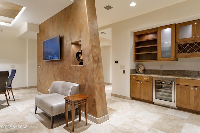 bar with beverage cooler, baseboards, visible vents, and bar area
