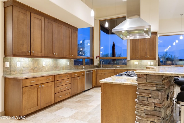 kitchen with brown cabinetry, decorative backsplash, island range hood, and light stone countertops