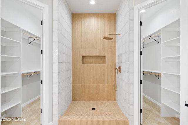 bathroom with recessed lighting, tiled shower, and a spacious closet