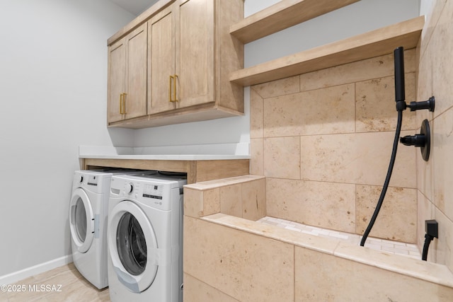 laundry area with separate washer and dryer, cabinet space, and baseboards