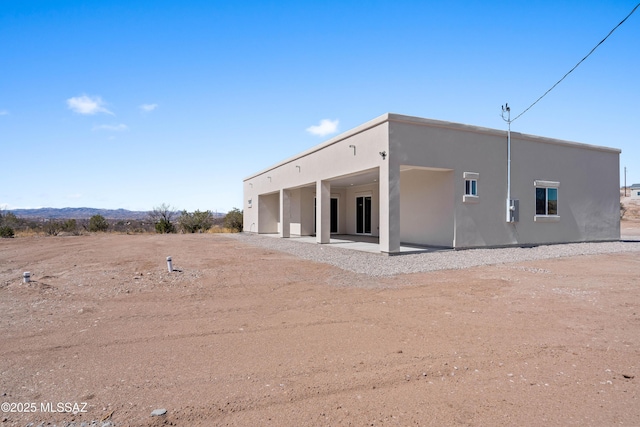 rear view of house with a patio and stucco siding