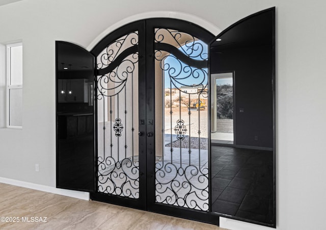 interior space with arched walkways, baseboards, french doors, and a gate