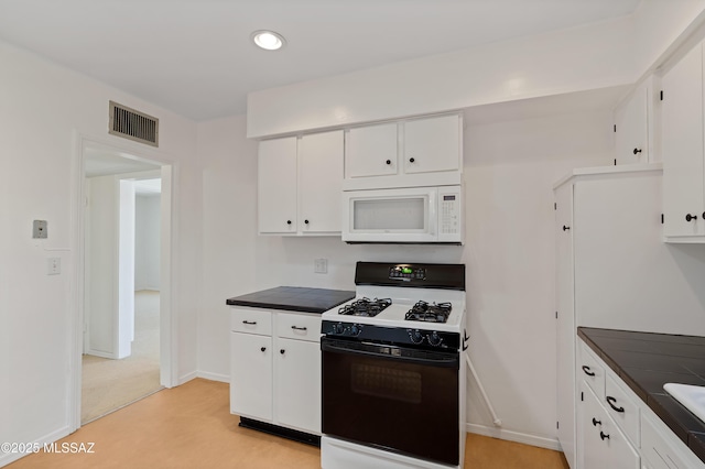 kitchen featuring white cabinets, gas stove, baseboards, white microwave, and visible vents