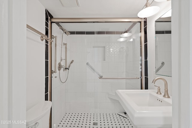 bathroom featuring a sink, a shower stall, and toilet