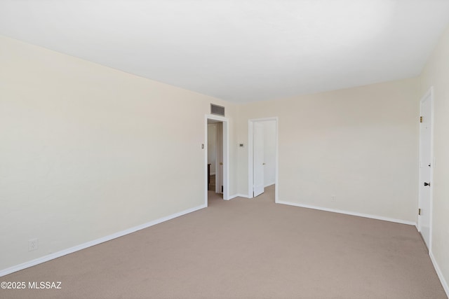 carpeted spare room featuring baseboards and visible vents