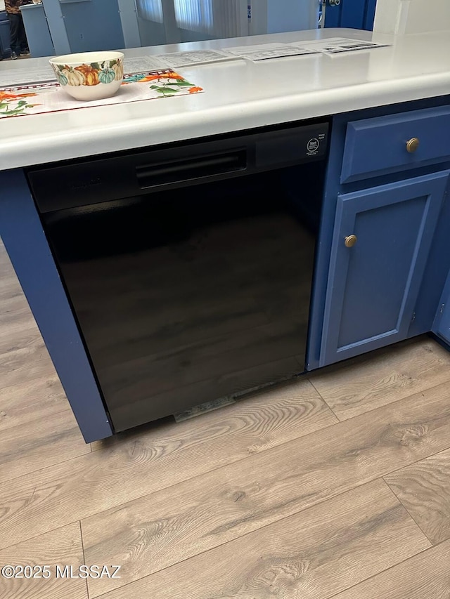 room details with black dishwasher, light countertops, blue cabinetry, and light wood-style floors