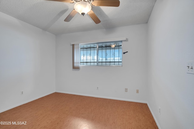 spare room featuring a textured ceiling, baseboards, a ceiling fan, and wood finished floors